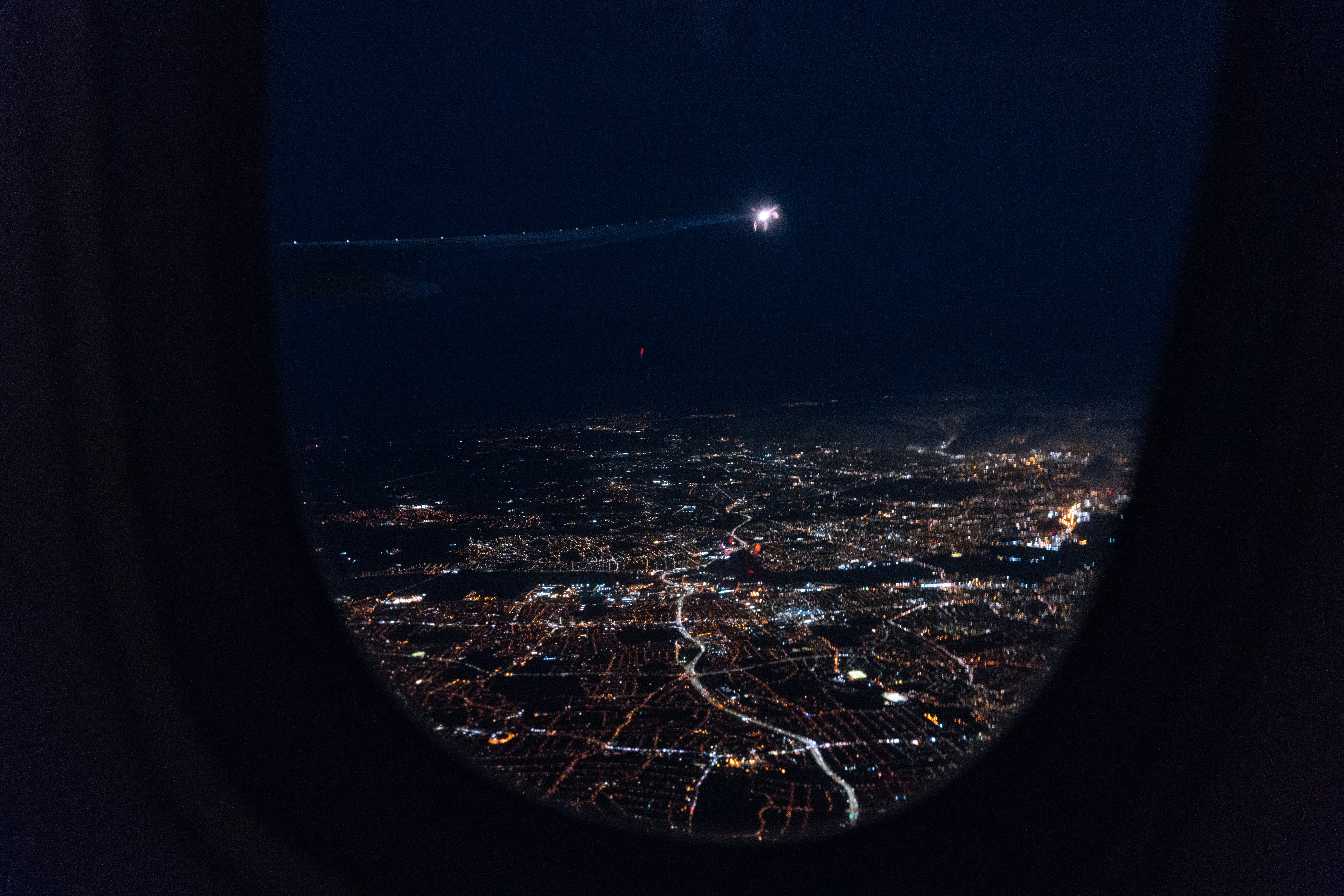 View of city lights from a plane window during a night flight